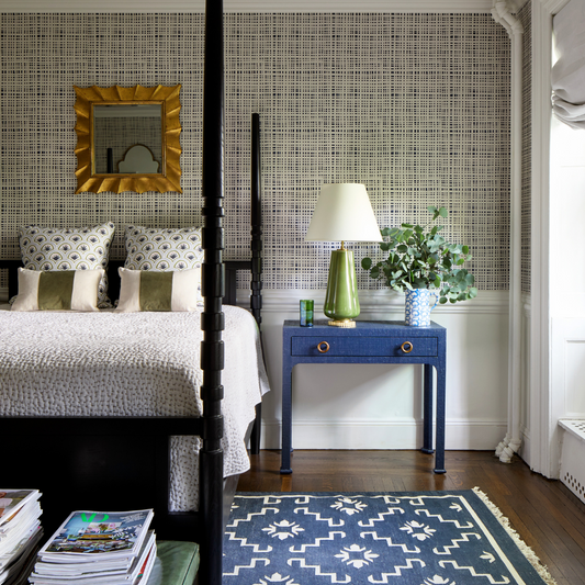 Navy gingham wallpaper in a bedroom with white wainscoting and a black four poster bed styled with white sheets and blue and green art deco custom pillows