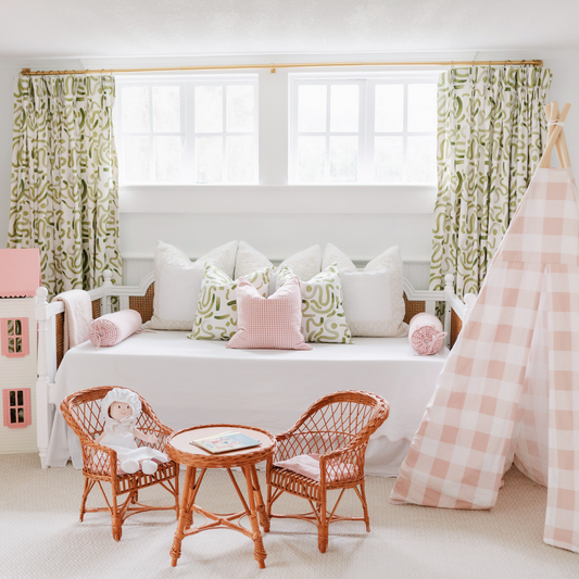 Moss abstract curtain panels hanging on a rod behind a white day bed in a. nursery with a pink gingham tent and rattan kid's furniture