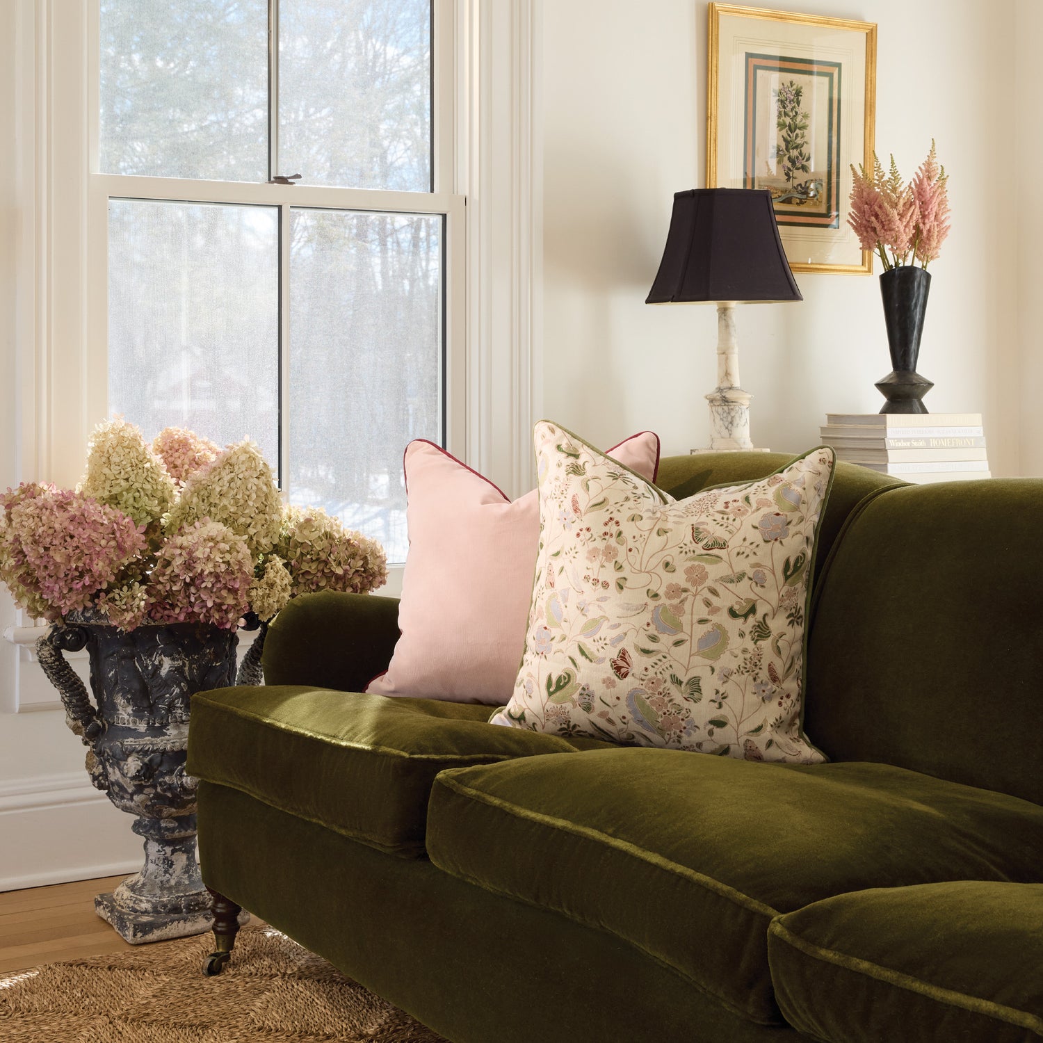 Gemma Rose decorative pillows on velvet sofa beside floral arrangement and classic lamp in cozy living room.