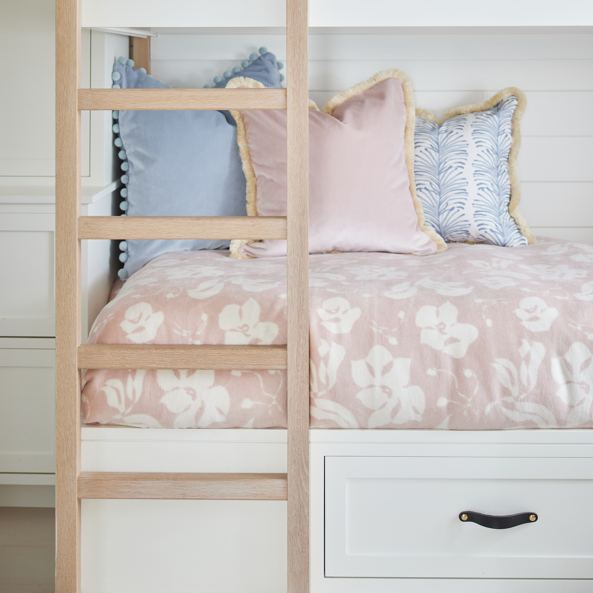 Pink bed with a floral blanket and Pink and Blue Velvet Pillows with complimentary trim.