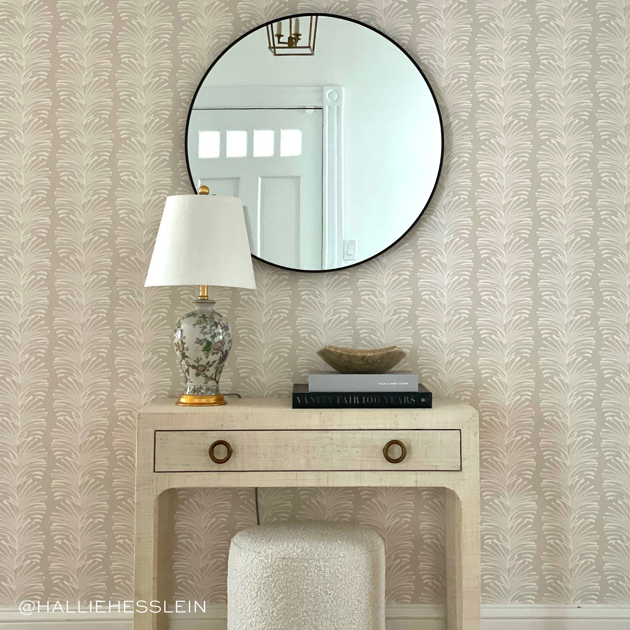 Corner styled with circular mirror on top of sand rectangular table with drawer and circular sofa chair under. Photo taken by Hallie Hesslein