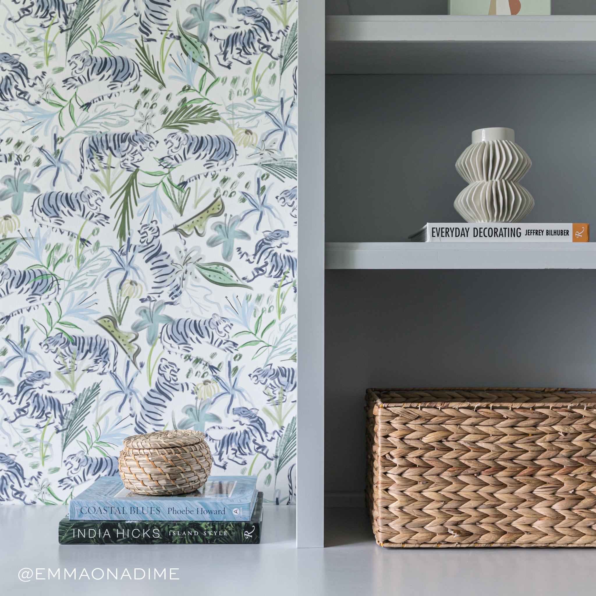 Office Close-Up styled with Green Tiger Printed Wallpaper and two books stacked on top of blue furniture and decorations on shelfs. Photo taken by Emma On A Dime
