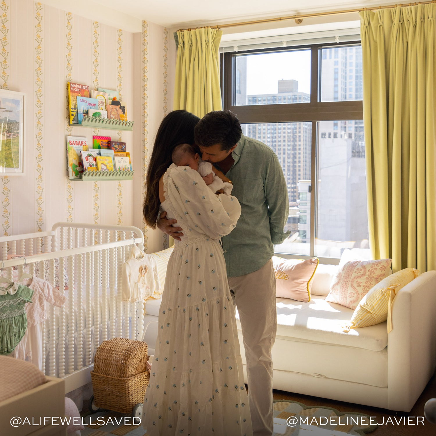 yellow lime green velvet curtains hung in front of an illuminated window with a white couch in front of the window and a mother and father standing hugging a baby in front of the couch