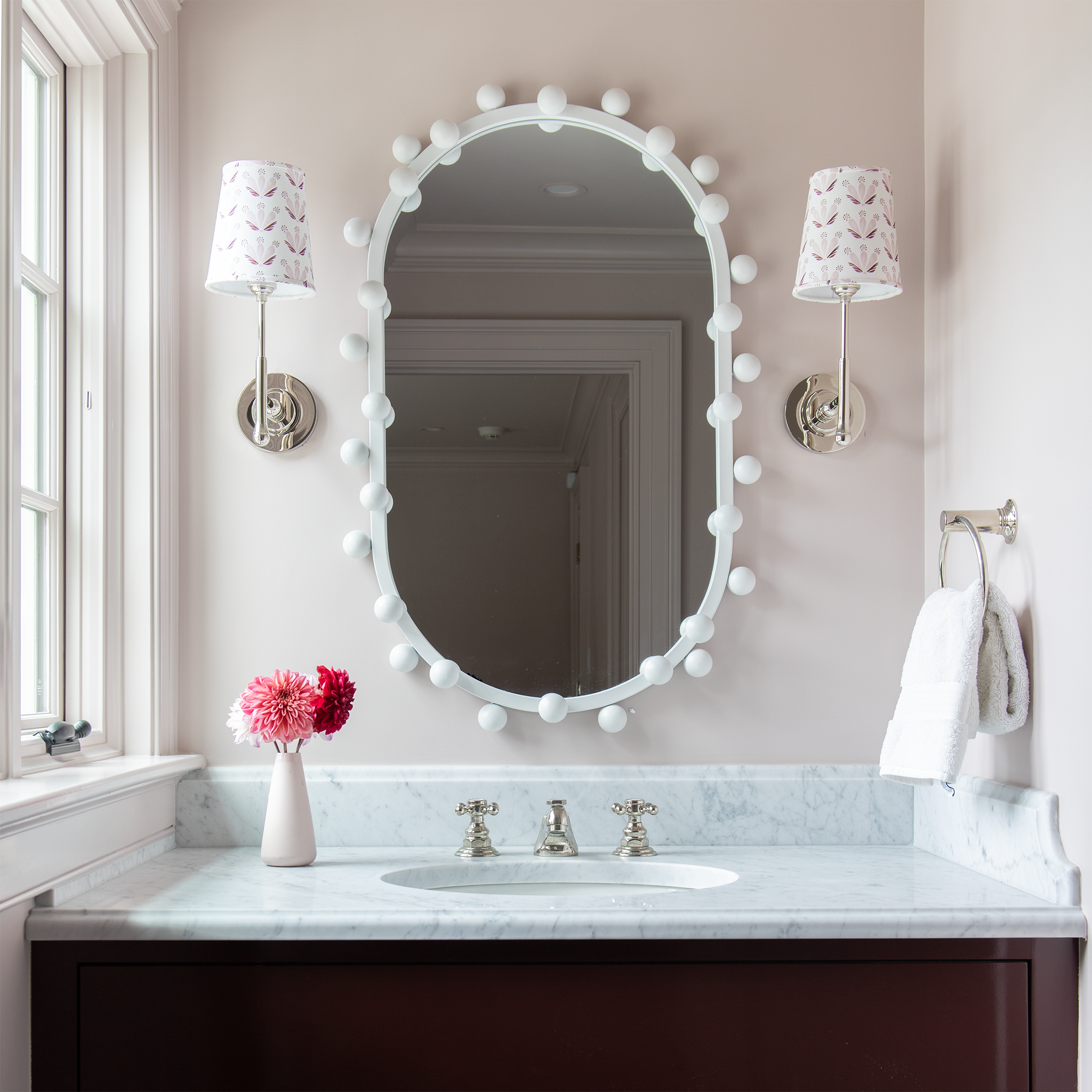 Bathroom vanity with pink and red flowers on it and a white mirror on the wall