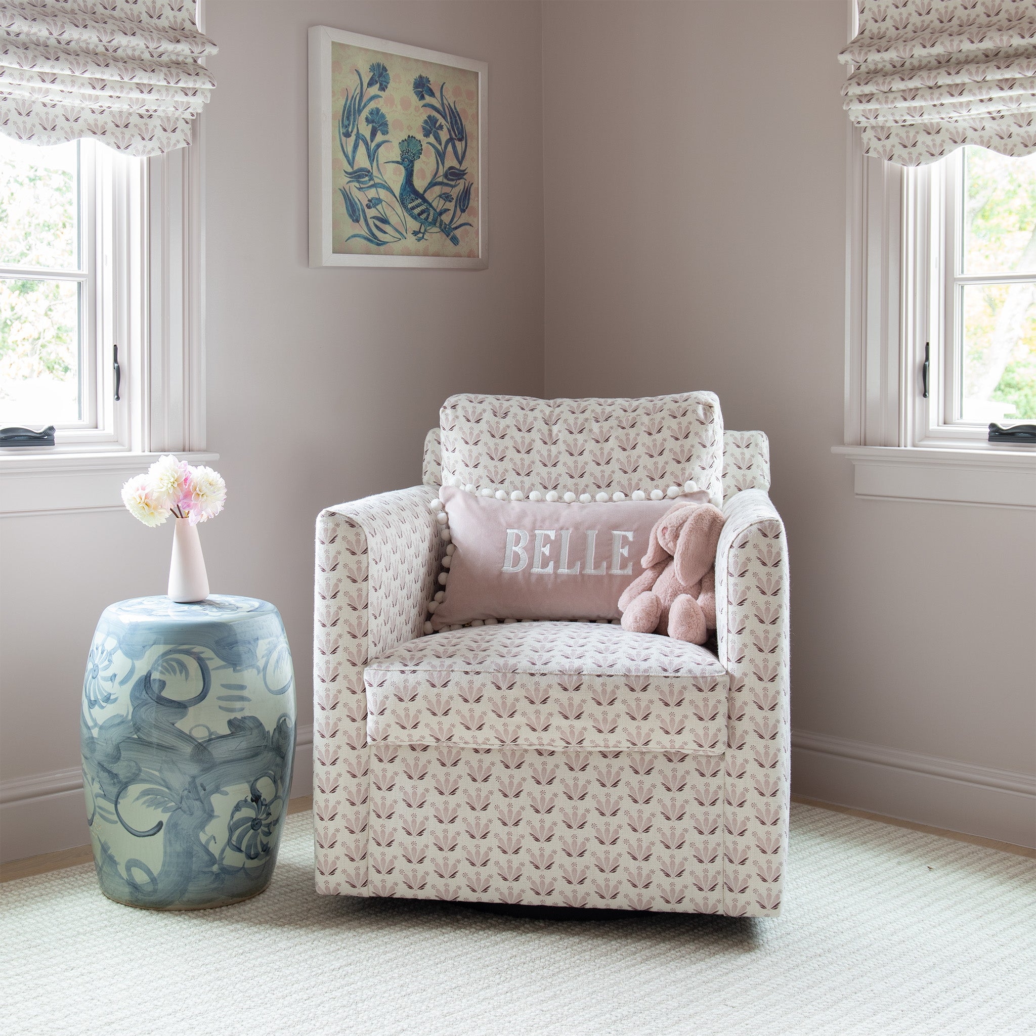 Nursery room corner close-up styled with Pink & Burgundy Drop Repeat Floral Printed Curtains matching the Pink & Burgundy Drop Repeat Floral Printed Sofa couch with Pink Velvet Monogrammed pillow next to blue and green small table with flowers in pink vase on top