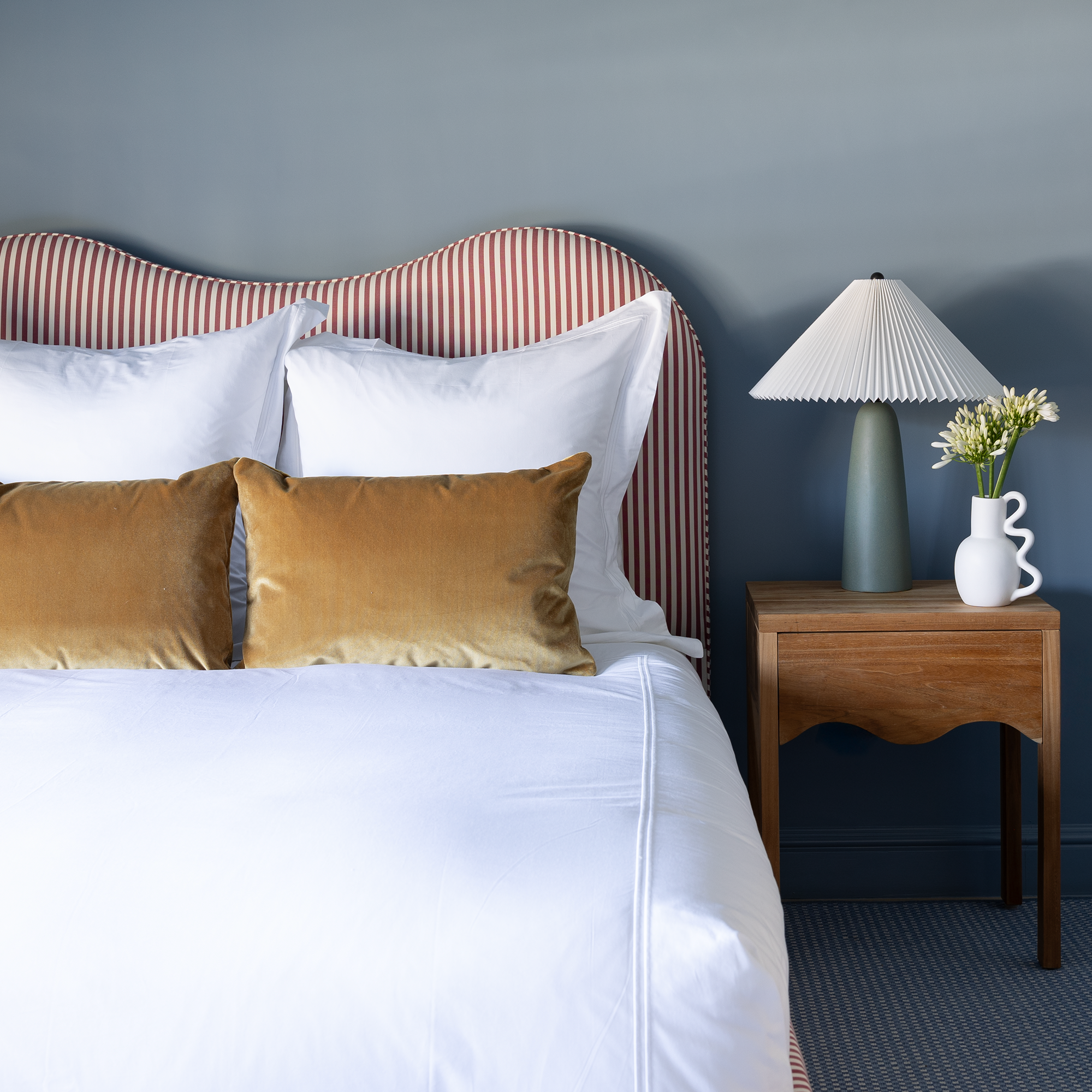 Louisa Cranberry Vertical bed with sculptural headboard in custom Pepper Home fabric, styled with white bedding and golden pillows.