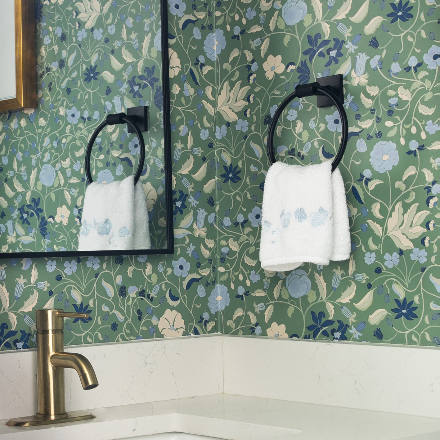 Lulie Parsley custom wallpaper with hand-painted floral pattern brightening a bathroom corner with towel and brass faucet.