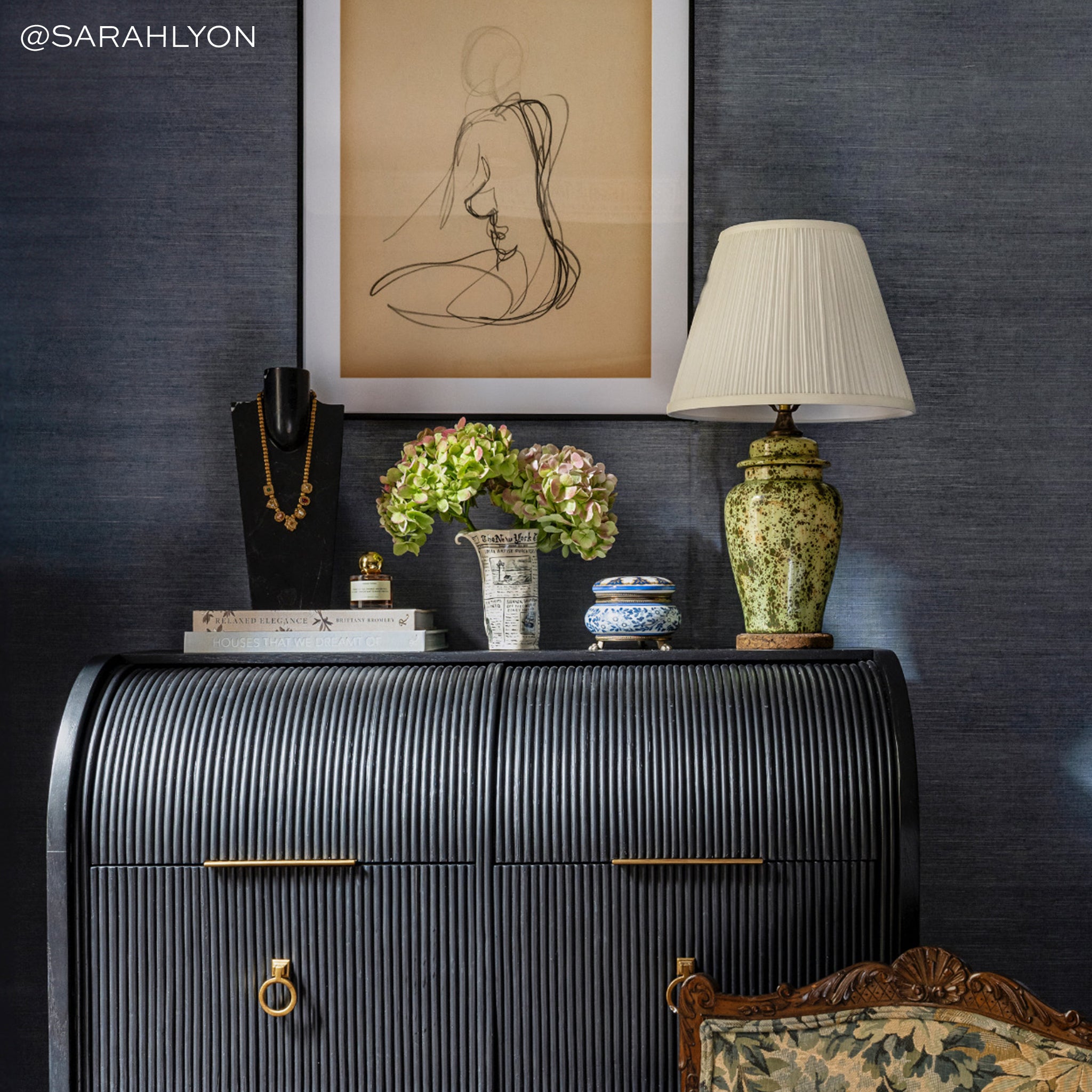 Deep blue-grey textured grasscloth wall covering with curated decorative accents and warm ambient lighting in elegant room setting.