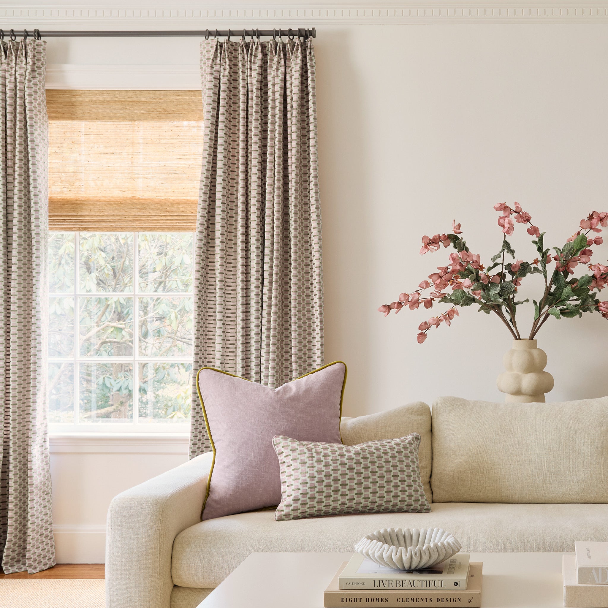  chenille and woven jacquard pink and citron geometric curtains on a metal rod in front of an illuminated window with a white couch and flowers in front