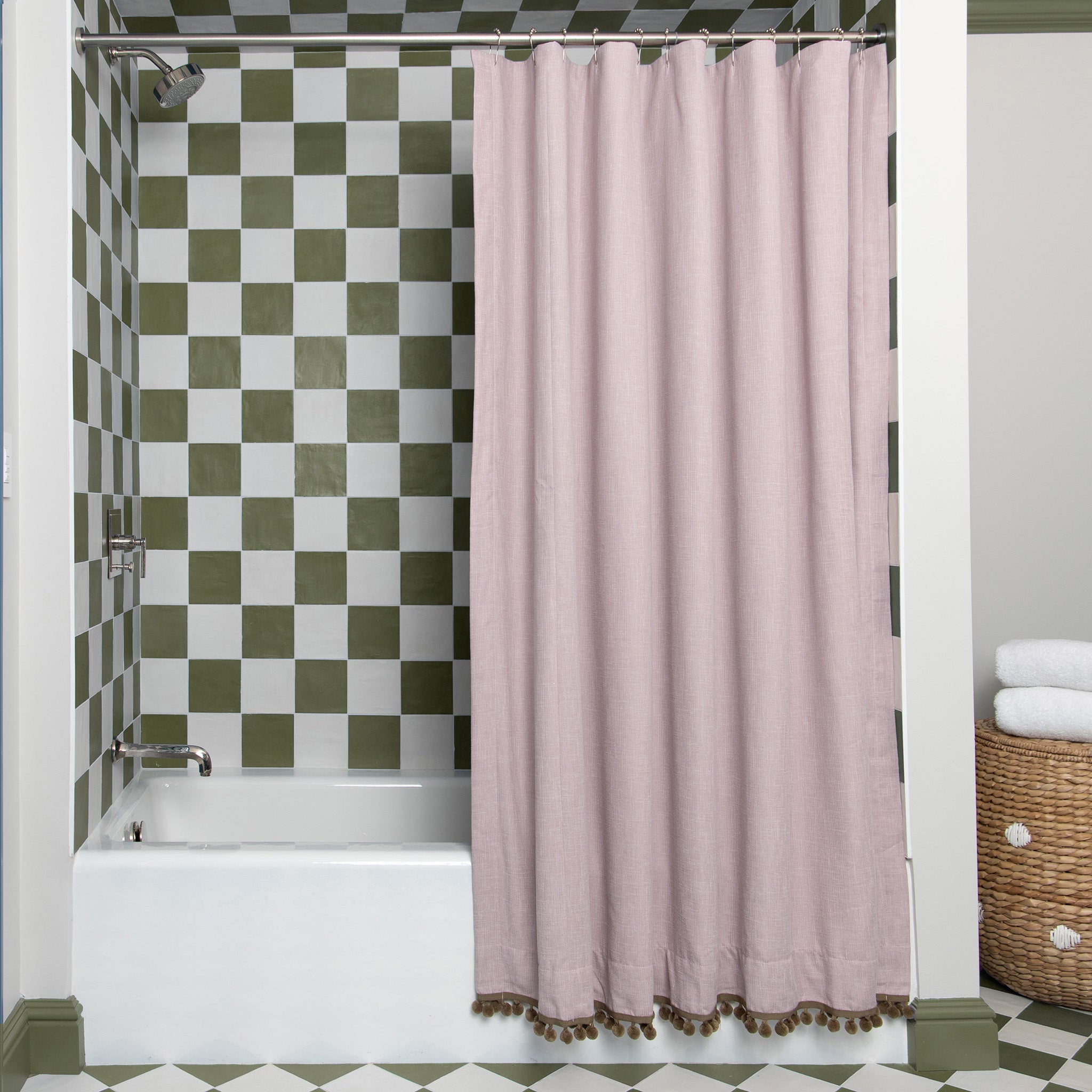 pink shower curtain hanging in front of a bathtub with green and white tiles