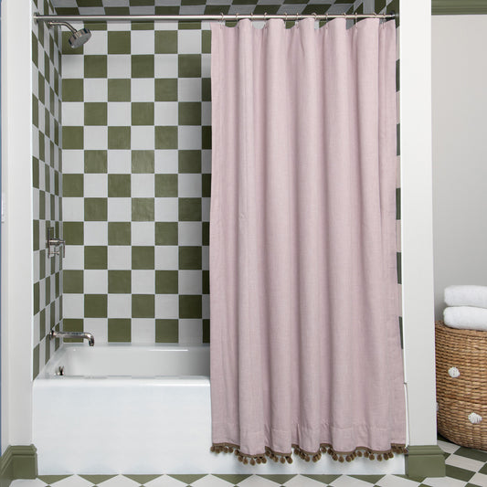 pink shower curtain hanging in front of a bathtub with green and white tiles