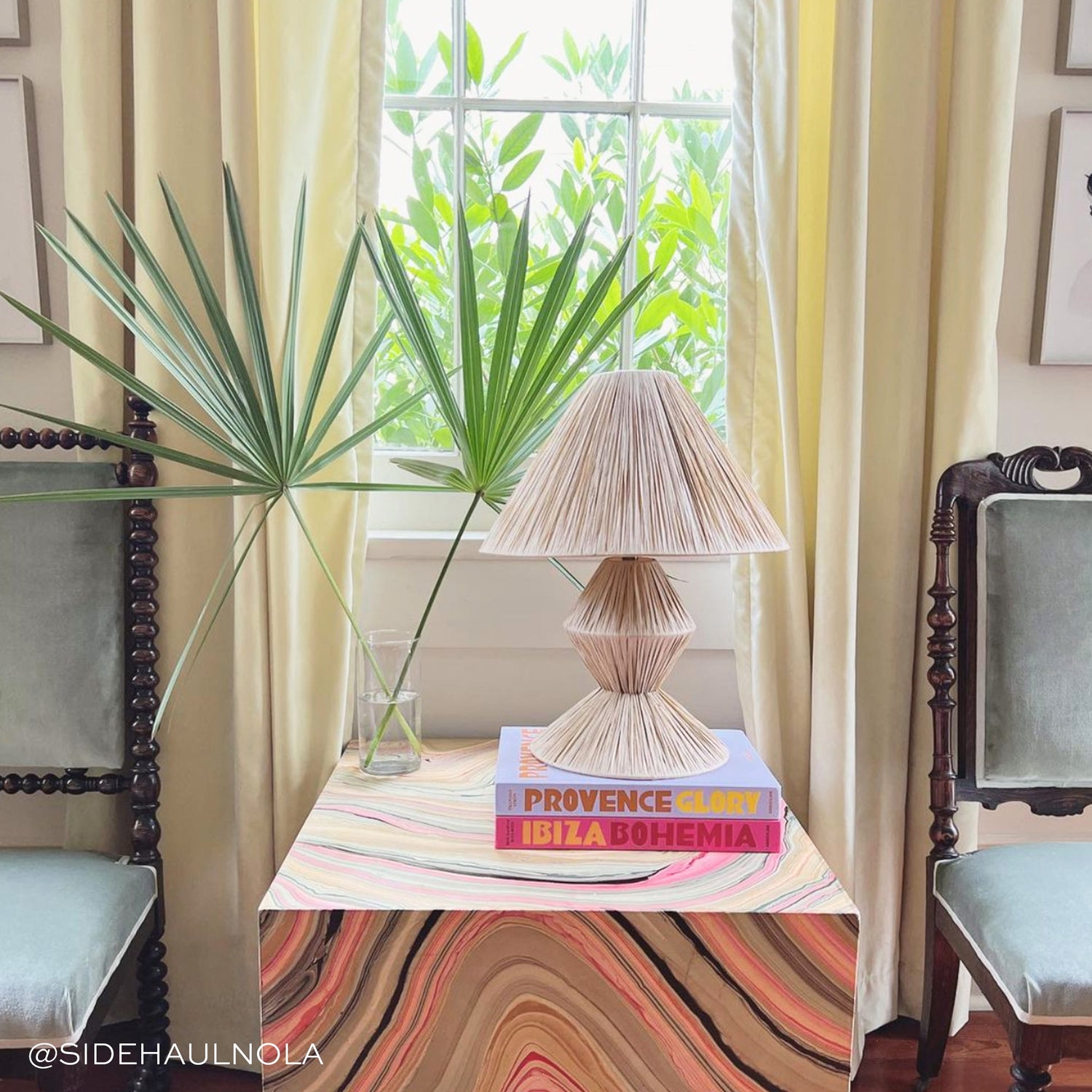 light green velvet curtain in front of a window with chairs and a table with books on it