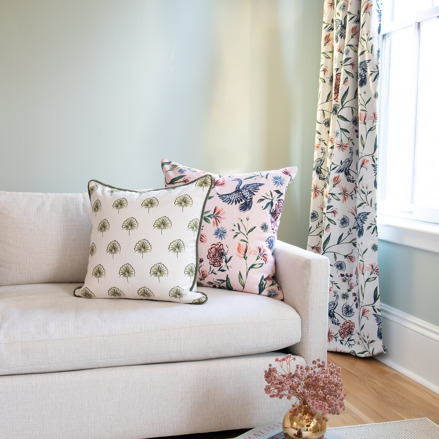 Living room styled with Cream Chinoiserie printed curtain next to white couch with Green Floral and Rose Chinoiserie pillows on top