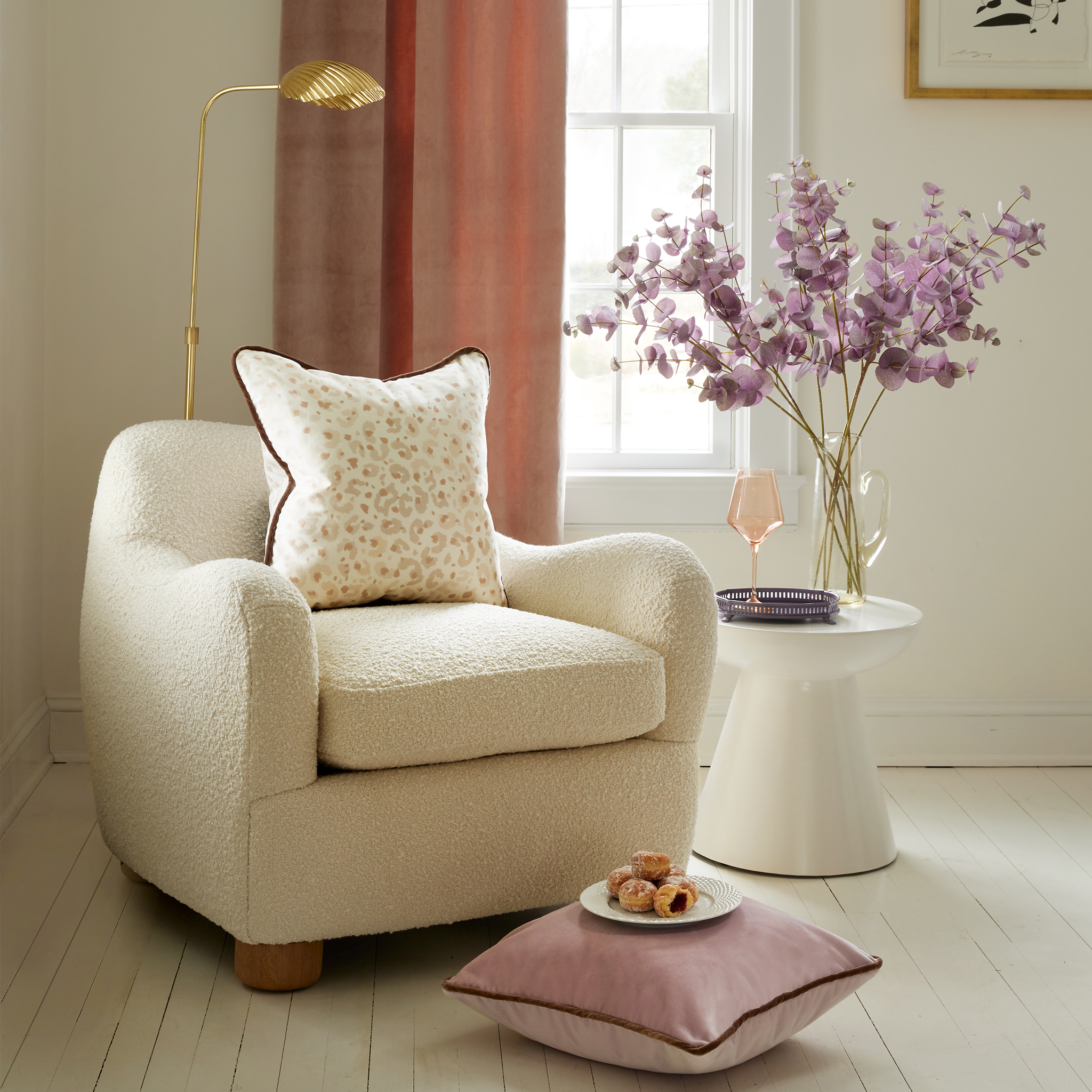 Living room corner styled with Mauve Velvet Curtains by white couch with Beige Animal Print Pillow on white sofa by Lilac Velvet pillow on the floor with dessert plate on top