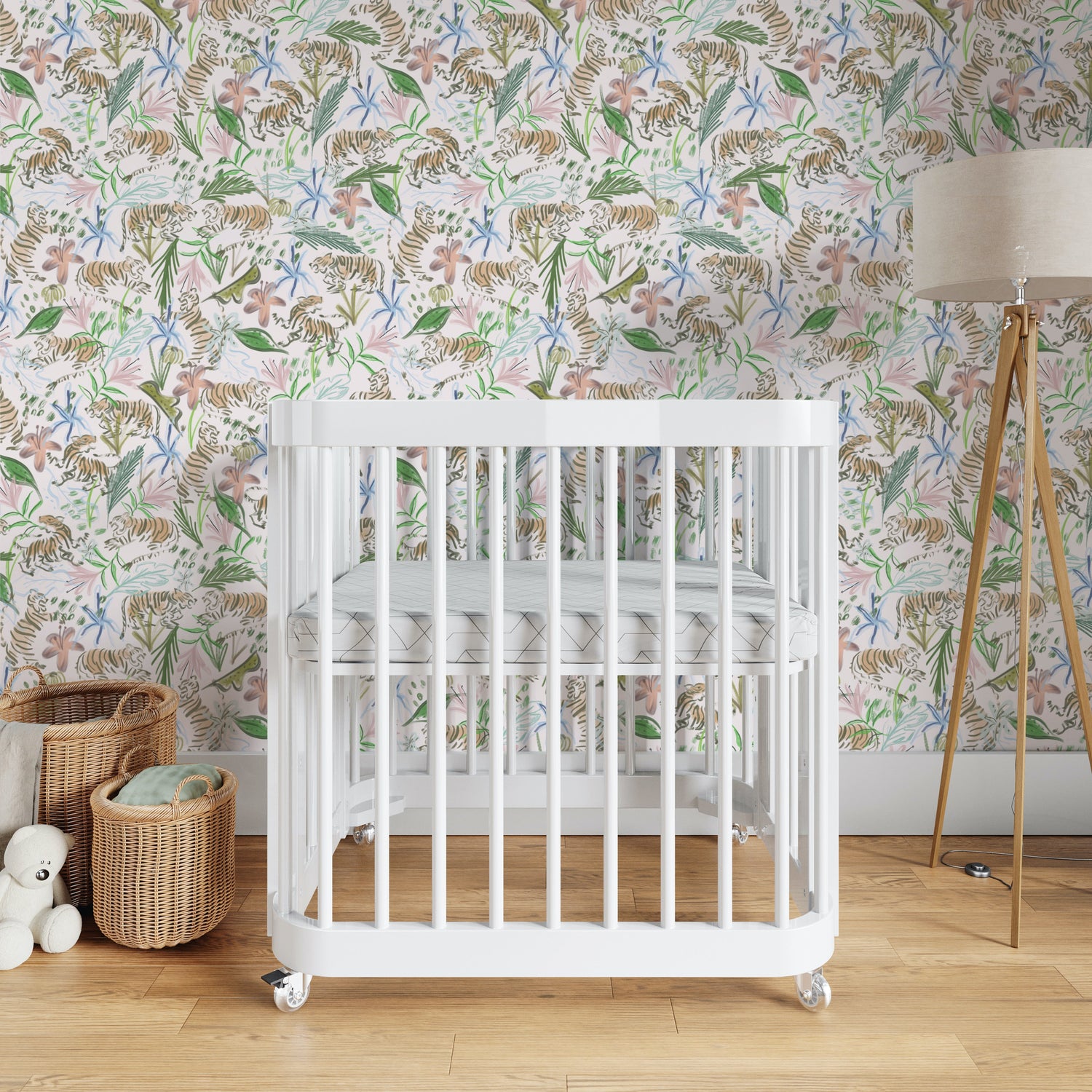 Nursery room styled with Pink Chinoiserie Tiger Printed Wallpaper and white crib next to two baskets and wooden lamp on the other side
