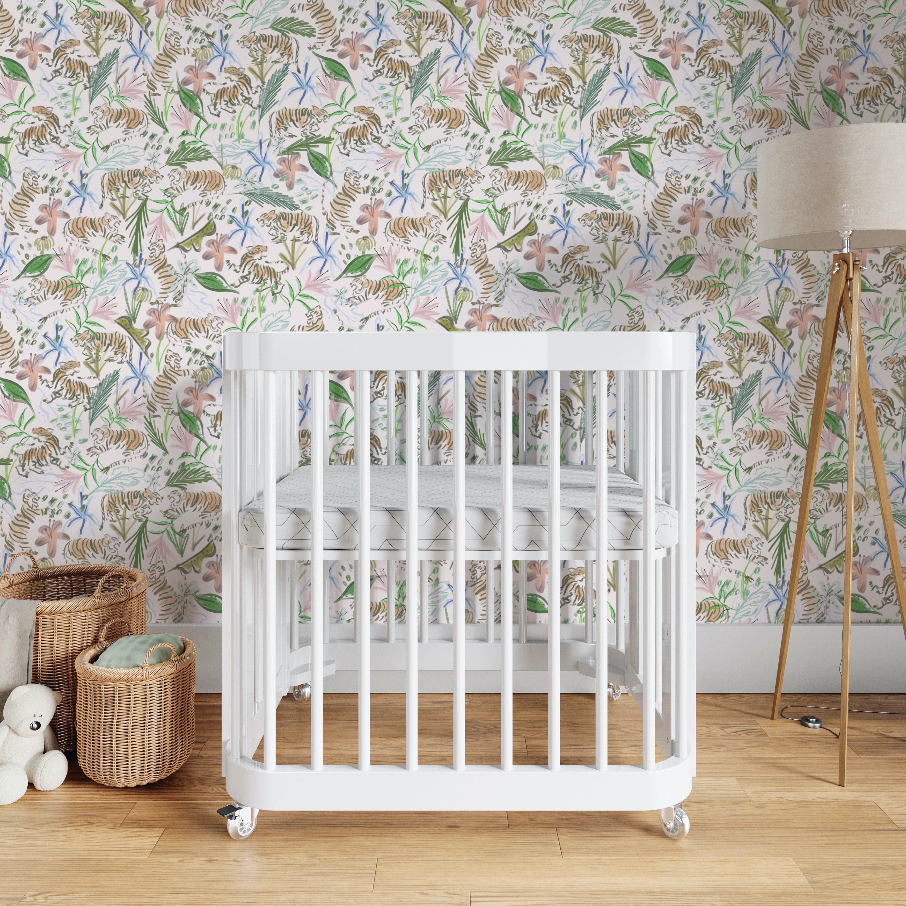 Nursery room styled with Pink Chinoiserie Tiger Printed Wallpaper and white crib next to two baskets and wooden lamp on the other side