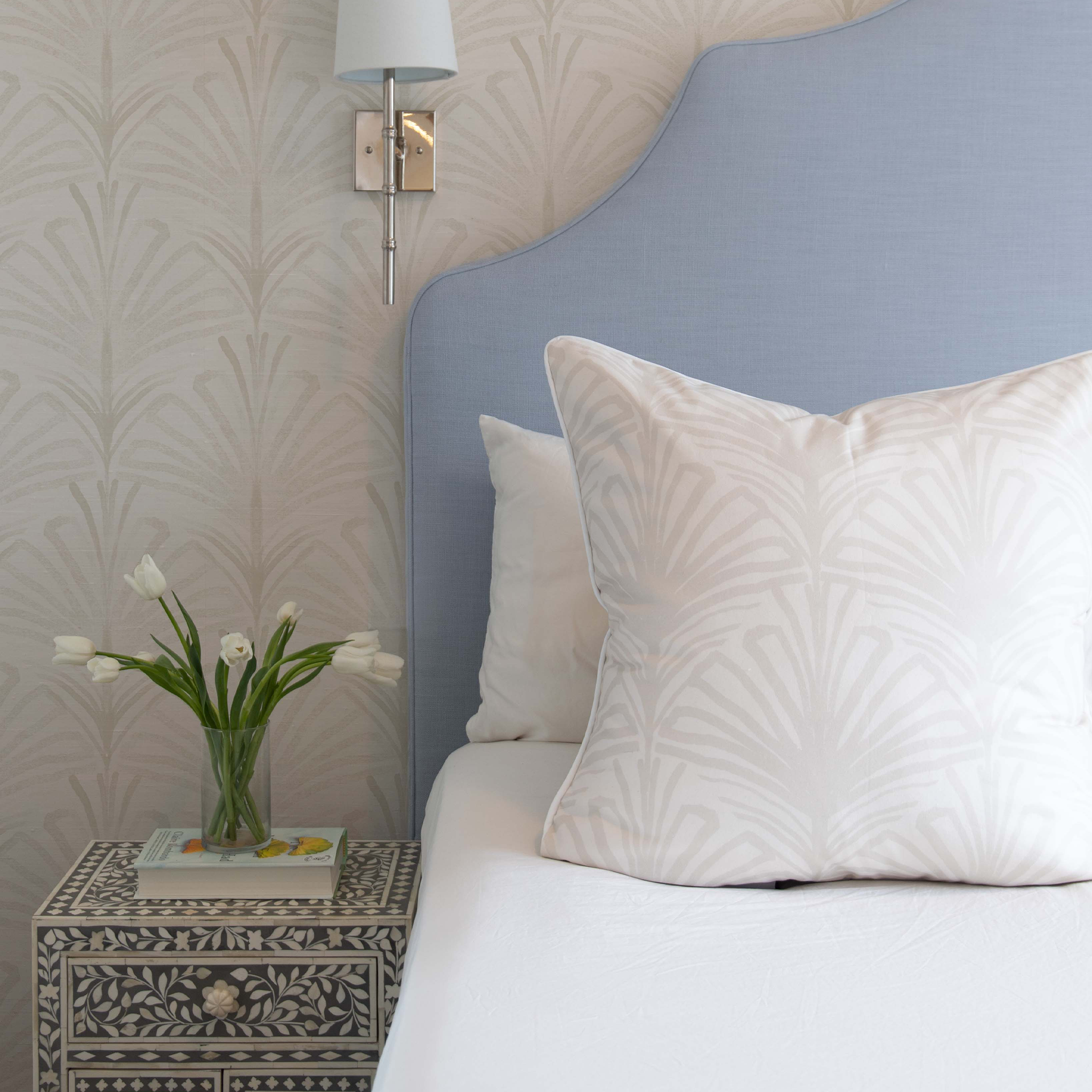 Suzy Snow pillow on bed with blue headboard and custom curtain-inspired wallpaper by Pepper Home.