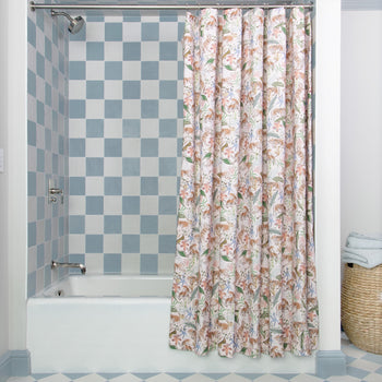 Pink Chinoiserie Tiger shower curtain hanging on rod in front of white tub in bathroom with blue and white tiles