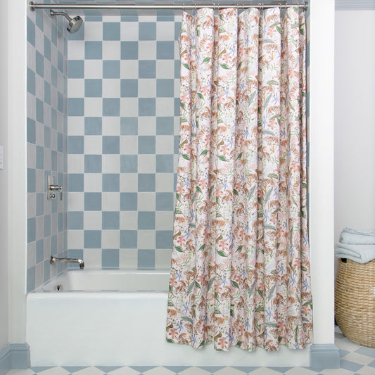 Pink Chinoiserie Tiger shower curtain hanging on rod in front of white tub in bathroom with blue and white tiles