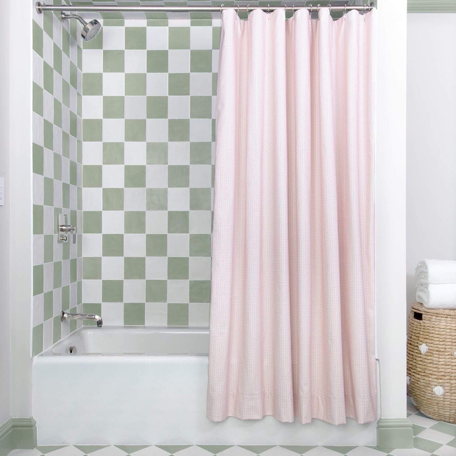 Pink Geometric Printed shower curtain hanging on rod in front of white tub in bathroom with green and white tiles