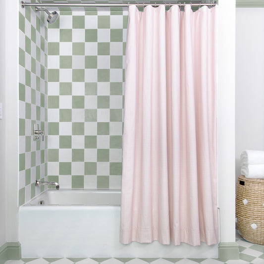 Pink Geometric Printed shower curtain hanging on rod in front of white tub in bathroom with green and white tiles