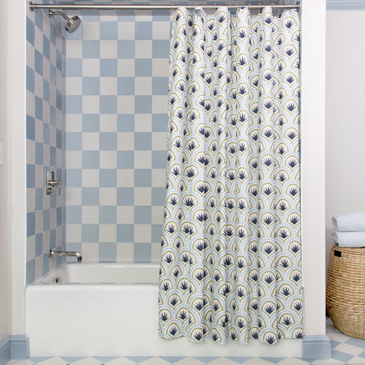 Art Deco Palm Pattern Printed shower curtain hanging on rod in front of white tub in bathroom with blue and white tiles