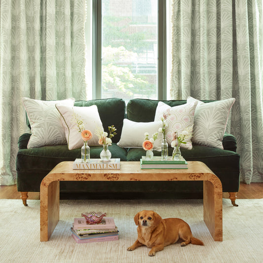 Green velvet couch with pink and green patterned pillows and dog in front of sage palm custom curtains