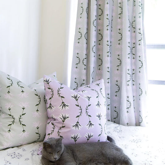 Bed with grey cat styled with a Lavender Botanical Ikat Custom Pillow and a Sage Green Botanical Ikat Custom Pillow next to a Sage Green Botanical Ikat Custom Curtain 