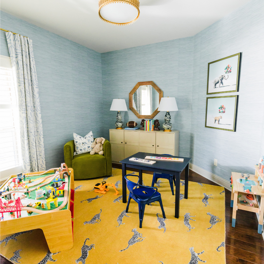 Kids playroom with sky blue grasscloth wallpaper and blue abstract custom curtains hanging in front of a window 