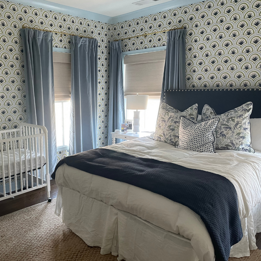 Bedroom with blue and green art deco palm wallpaper styled with sky blue velvet custom curtains and a navy upholstered bed with tiger chinoiserie blue pillows