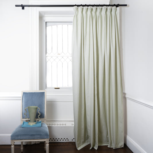 Moss green geometric custom curtain hanging on window in room with white walls and blue chair
