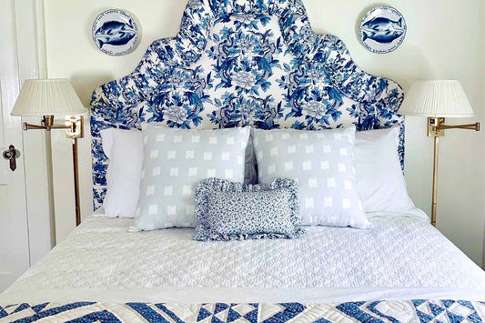 White bed with blue floral headboard styled with two Sky Blue Pattern Custom Pillows and two tall white lamps on each side of the bed