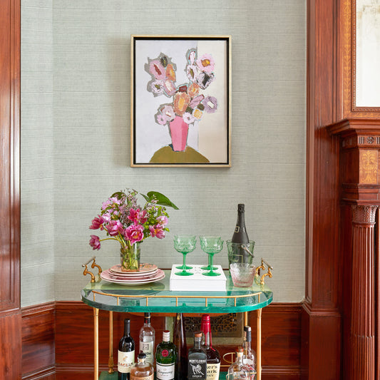 Sea salt solid grasscloth wallpaper on a wall styled with a bar cart with green classes and colorful flowers