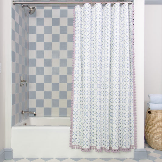 Blue and green shower curtain hanging on rod in front of white tub in bathroom with blue and white tiles