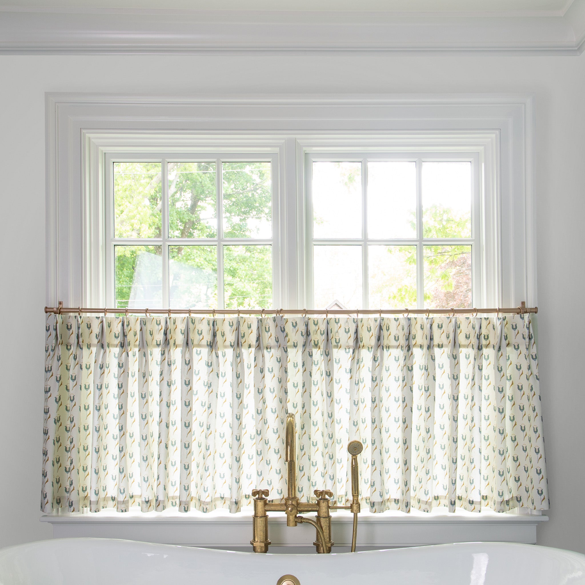 abstract floral blue printed cotton fabric curtains on a metal rod in front of an illuminated window in a bathroom