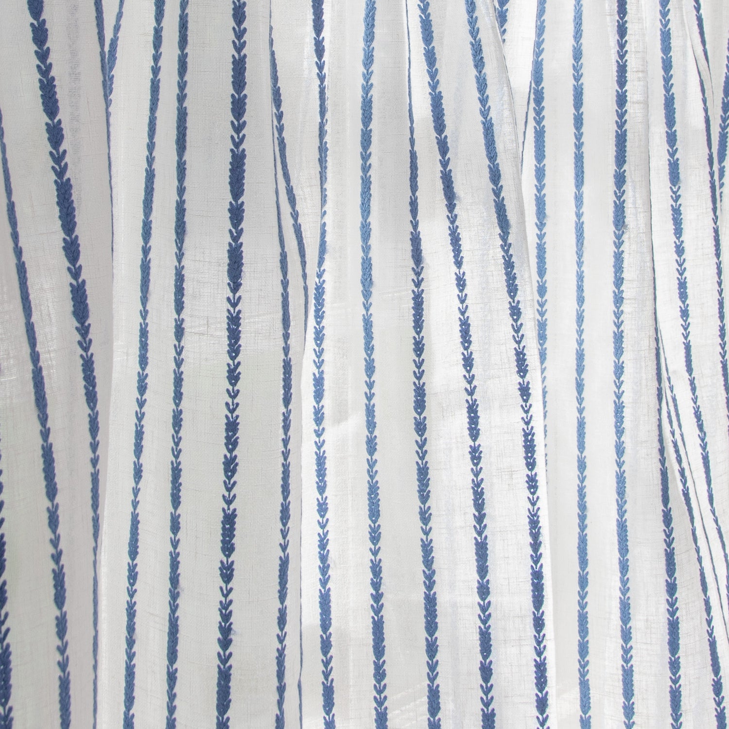 close up photo of white sheer curtain with blue embroidered stripe pattern