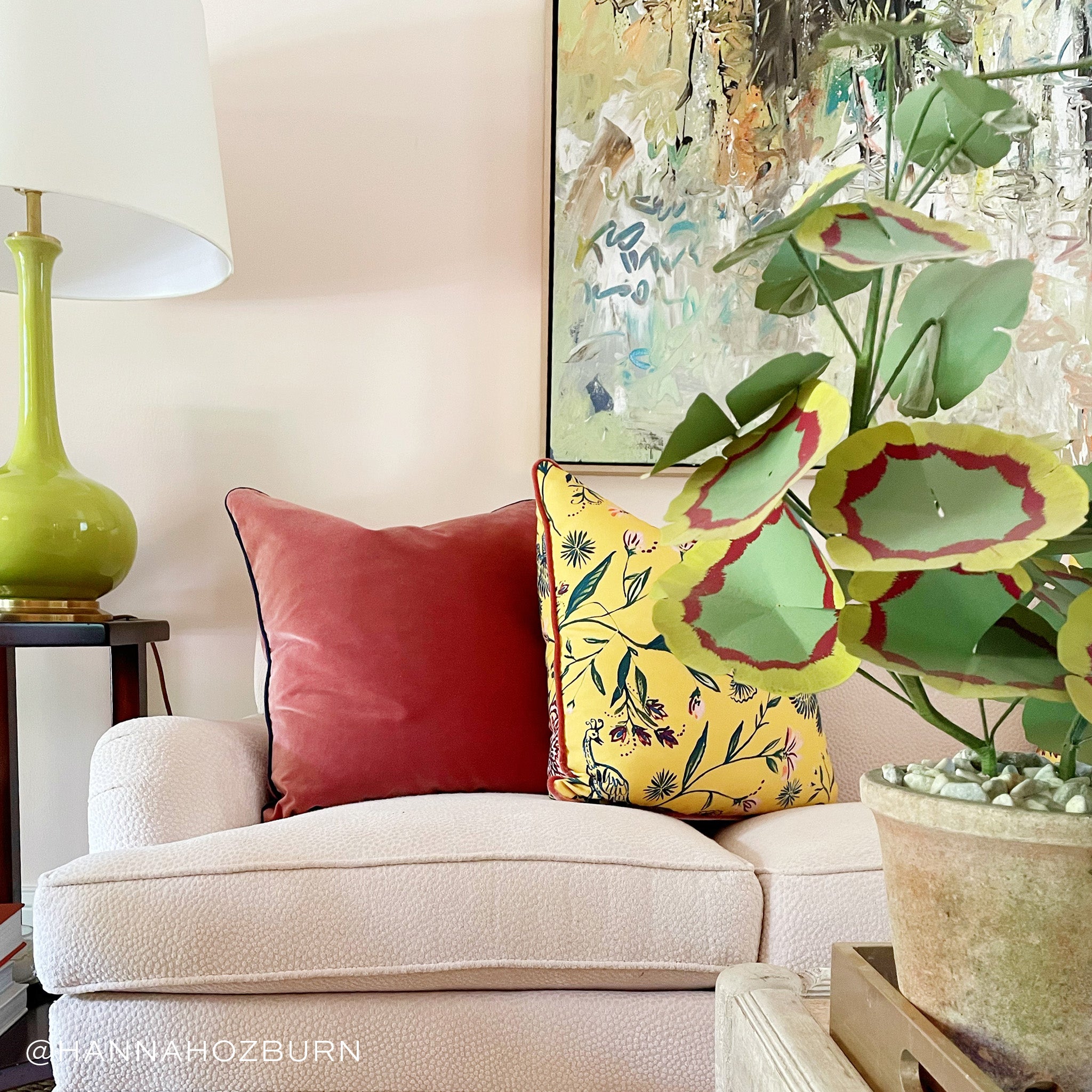 Coral Velvet and Yellow Chinoiserie custom pillows styled on white couch in a living room next to a green lamp and green and red plant. Photo taken by Hannah Ozburn.