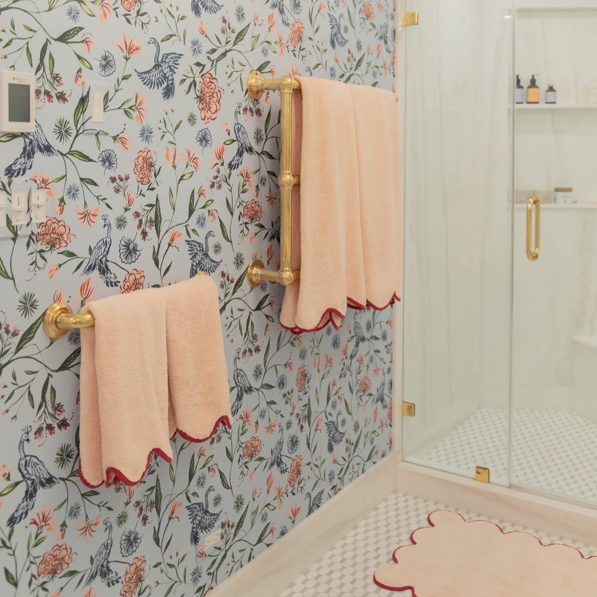 Blue Chinoiserie Printed Wallpaper on bathroom next to shower with coral towels hanging from two metal rods 