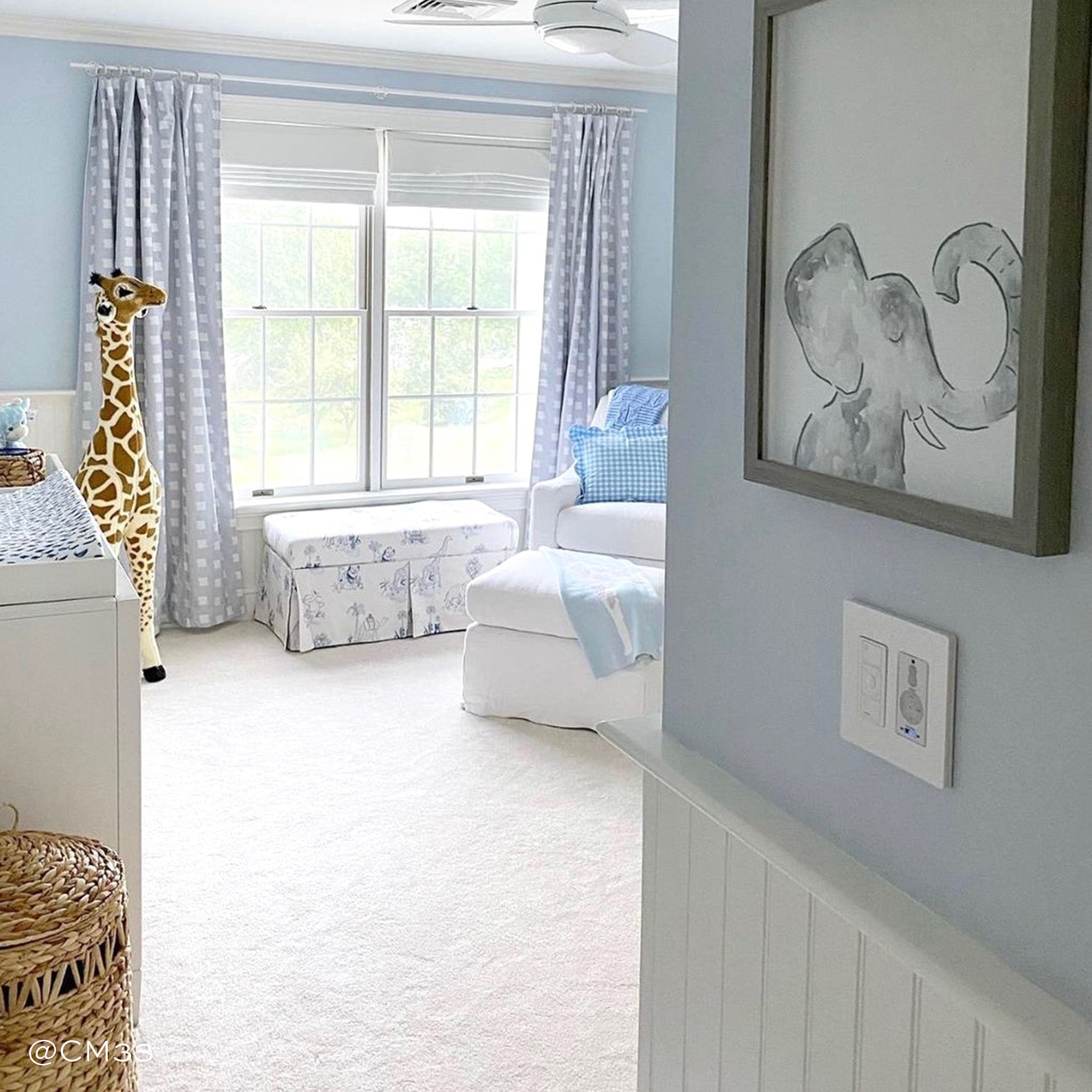 Nursery Room Styled with Sky Blue Pattern Printed Curtains with giraffe in front with white furniture and elephant painting in the entrance. Photo taken by CM33