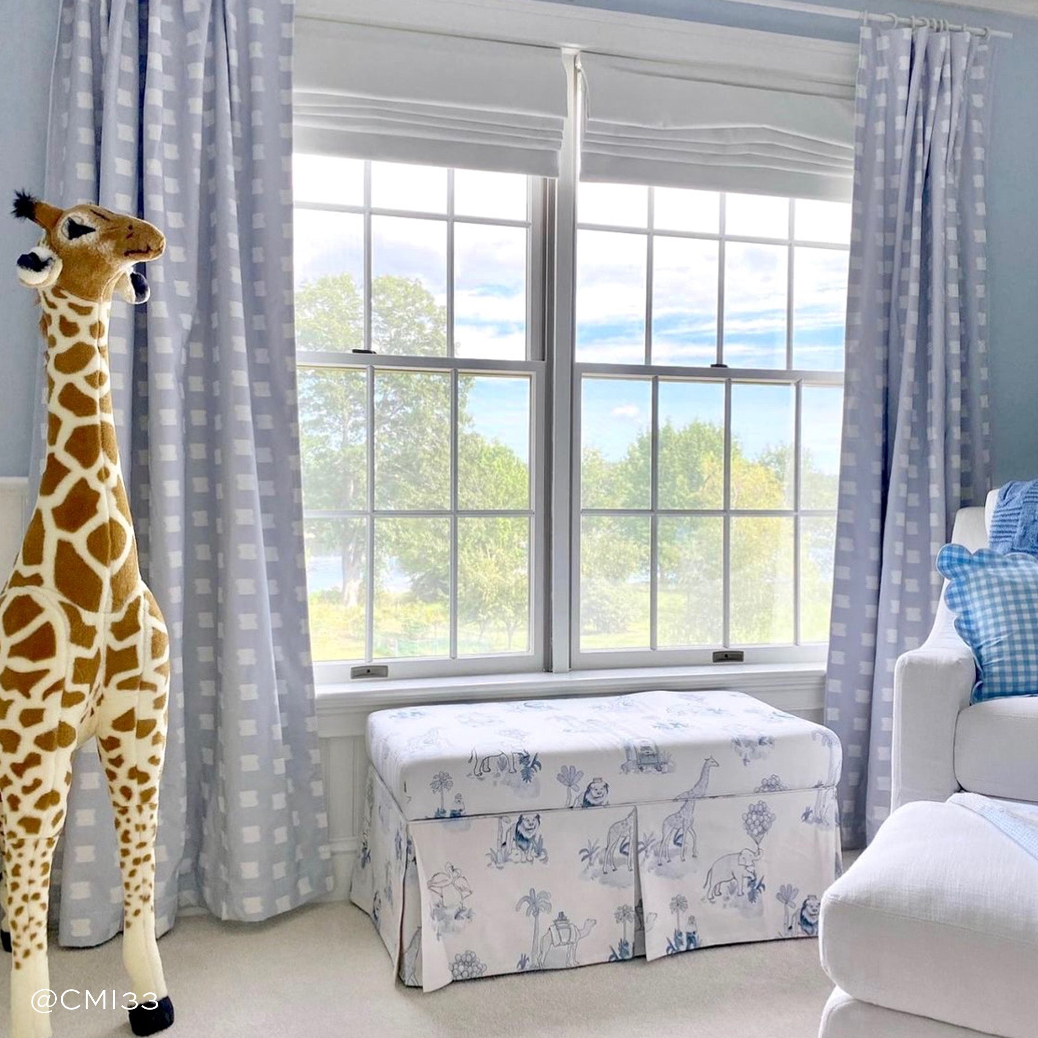 Nursery Room Styled with Sky Blue Pattern Printed Curtains with giraffe in front with white furniture. Photo taken by CMI33