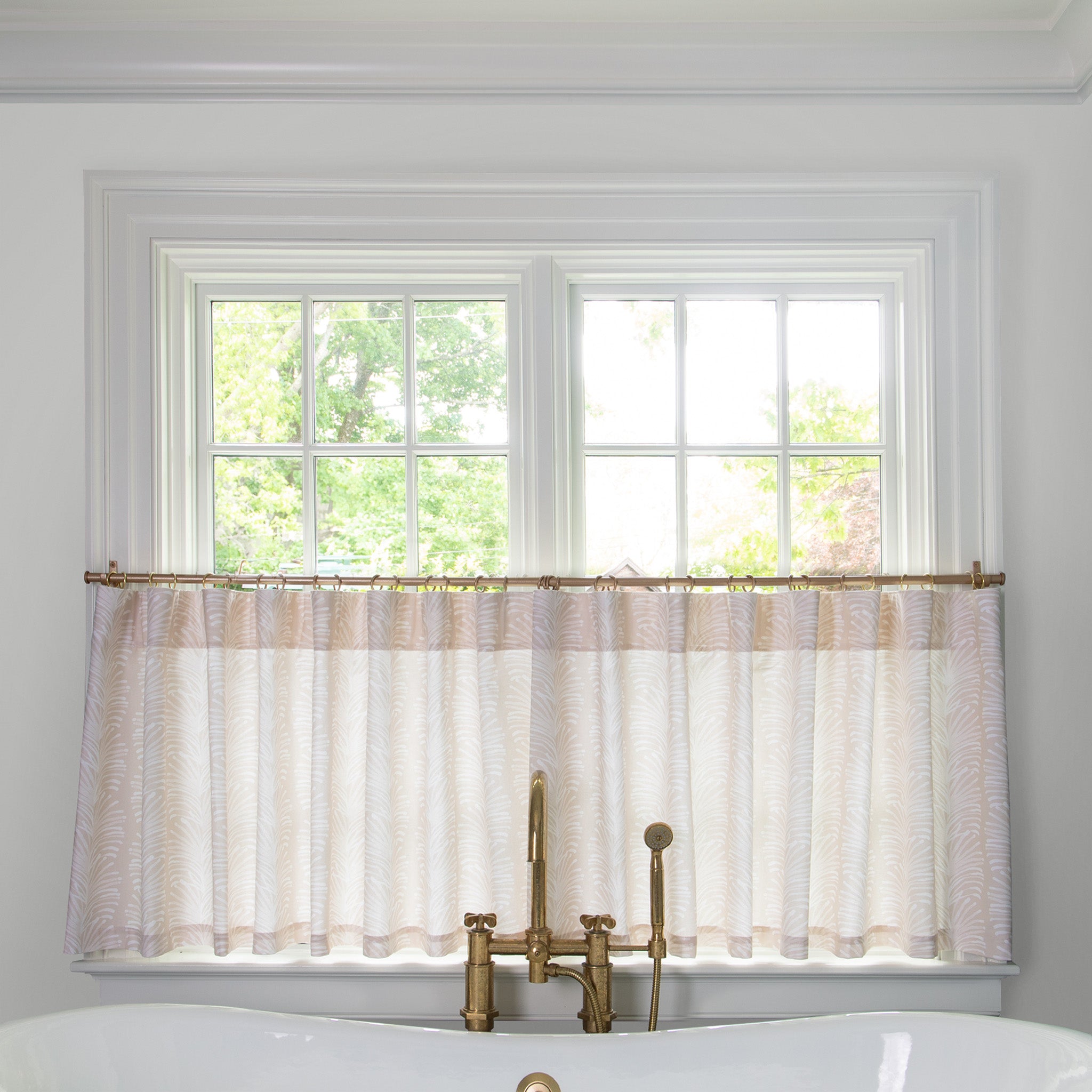 Beige Botanical Stripe Printed Cotton fabric curtain on a metal rod in front of an illuminated window in a bathroom 