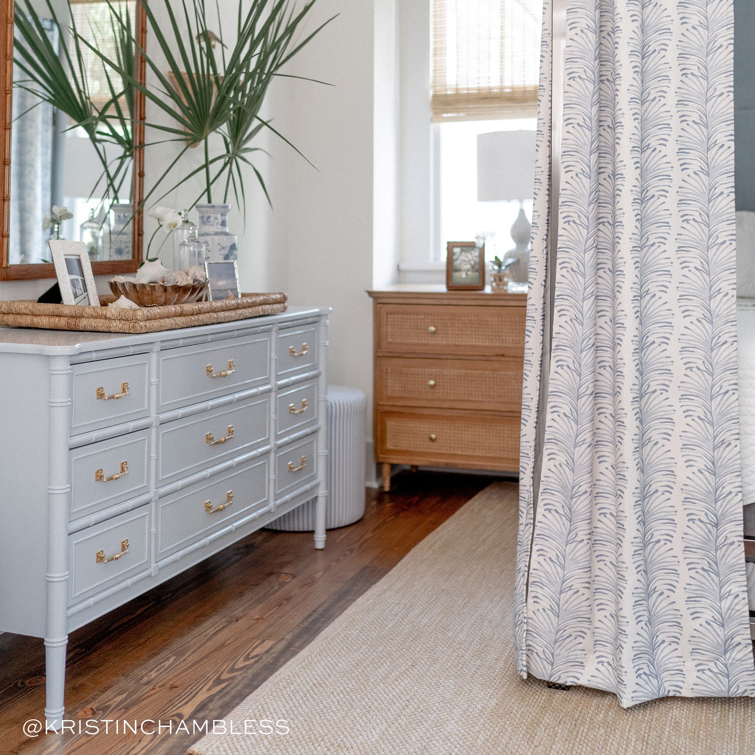 Bed styled with Sky Blue Botanical Stripe Printed Curtains hanging next to baby blue dresser with mirror hung on wall next to decorative plants. Photo taken by Kristin Chambless