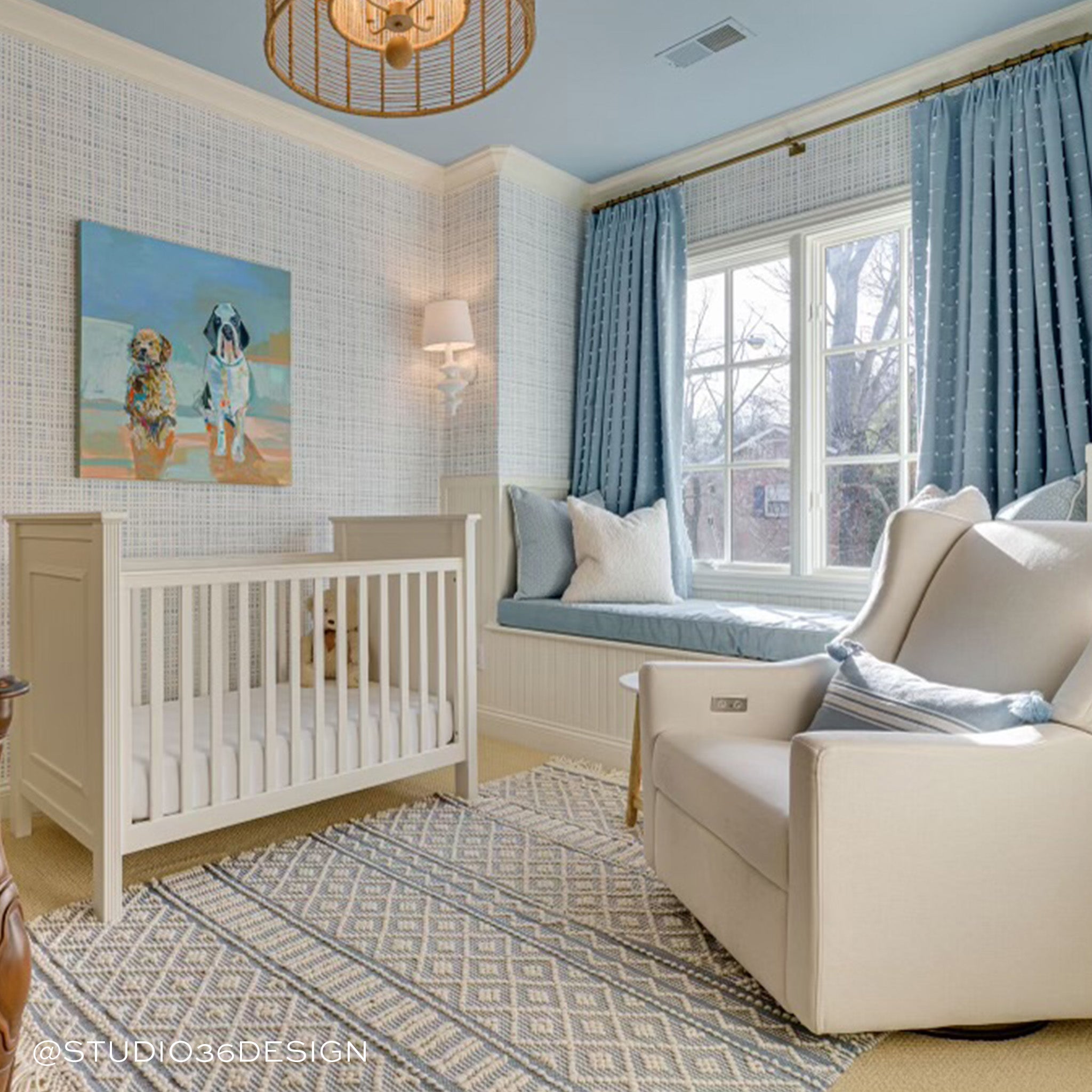 Nursery room styled with Sky Blue Gingham Printed Wallpaper next to white crib and white sofa couch by window with blue curtains and white and blue pillow. Photo taken by Studio 36 Design