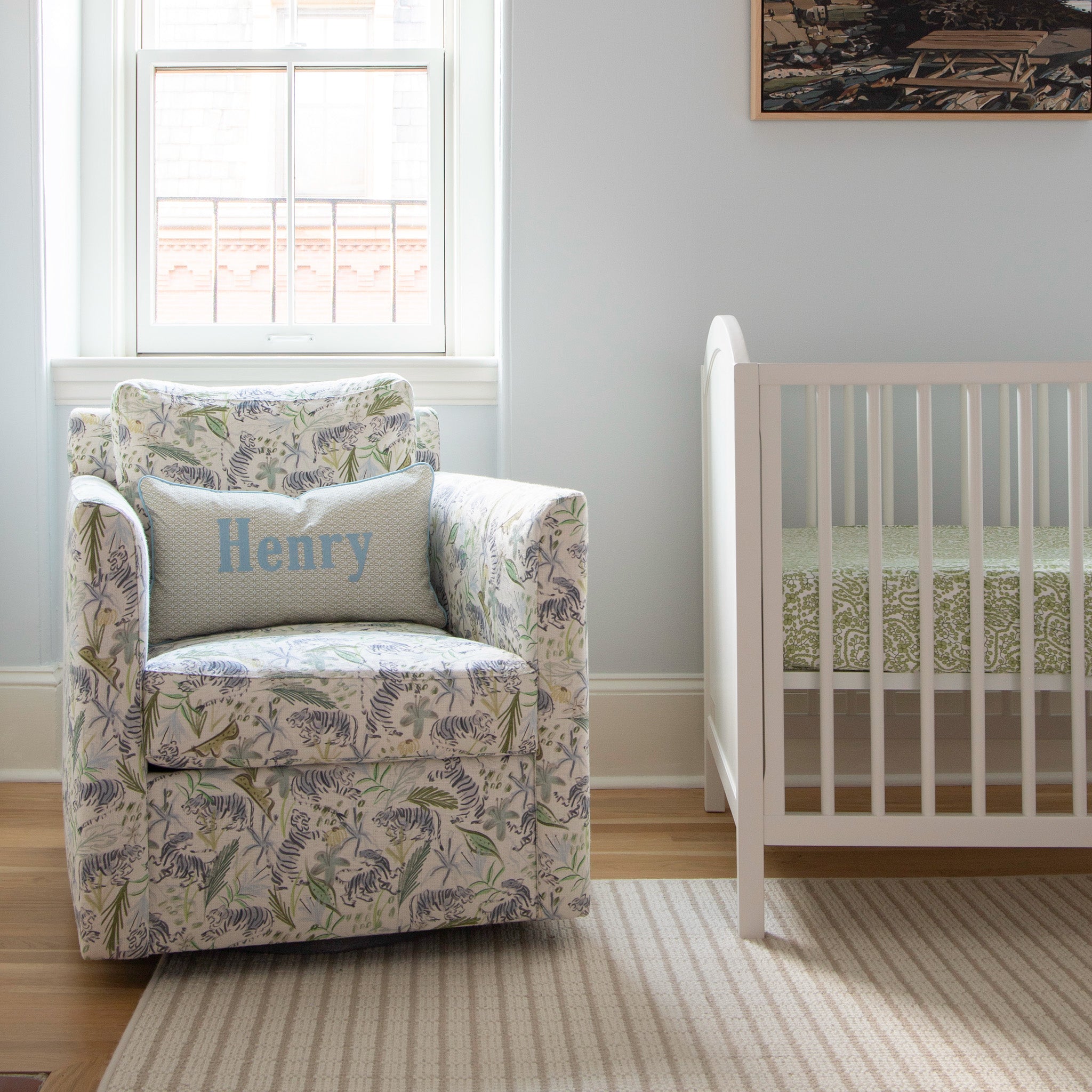 Nursery room corner styled with Moss Green Geometric Printed Monogrammed Pillow on Green Tiger Printed Linen Couch next to white crib