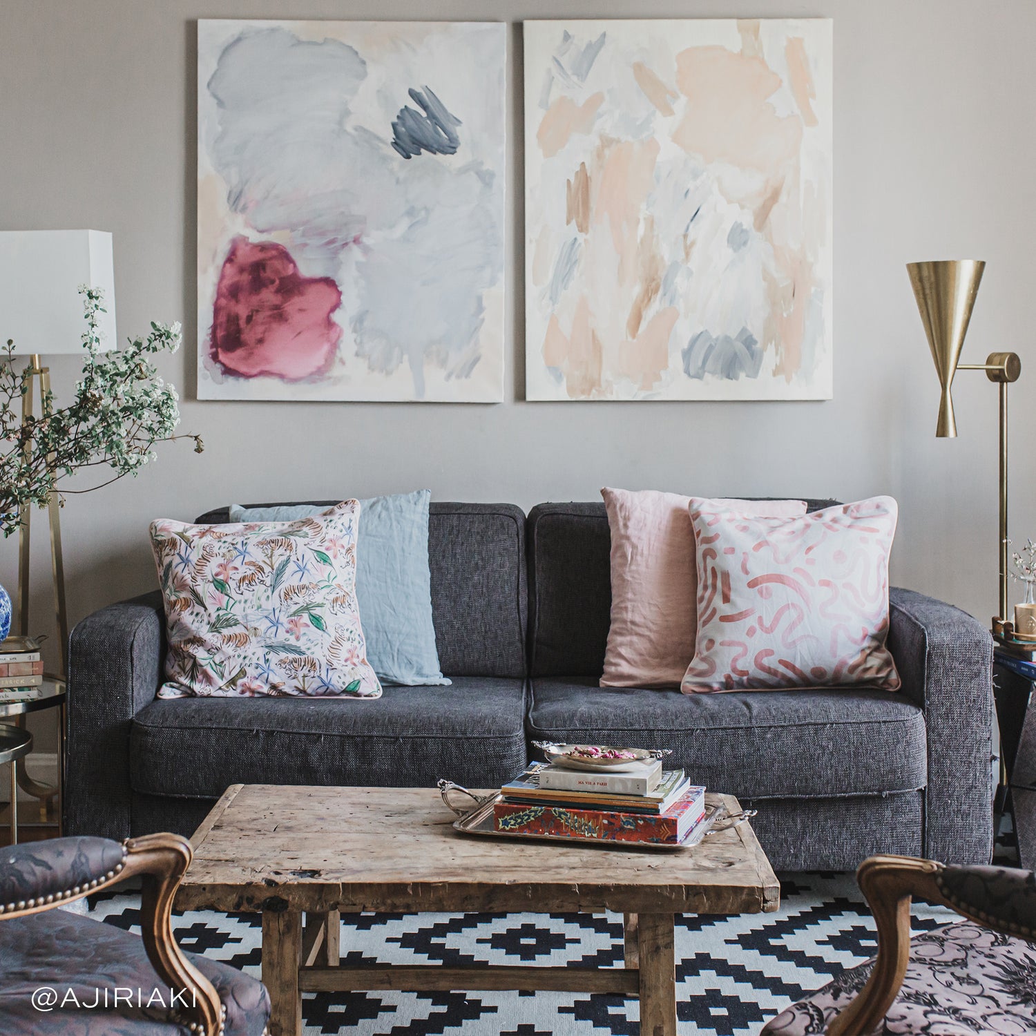 Living room styled with Pink Graphic Printed Pillow and Pink Chinoiserie Tiger Printed Pillow on grey couch by wooden coffee table with books stacked on top. Photo taken by Ajiri Aki