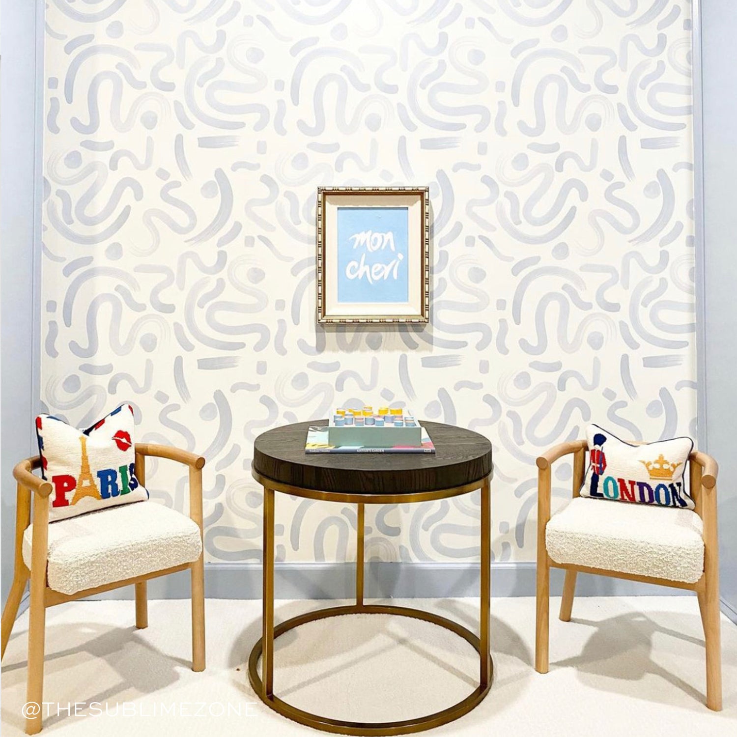 Room corner styled with Sky Blue Printed Wallpaper with frame hung in the middle over wooden coffee table and two wooden chairs surrounding it. Photo taken by The Sublime Zone