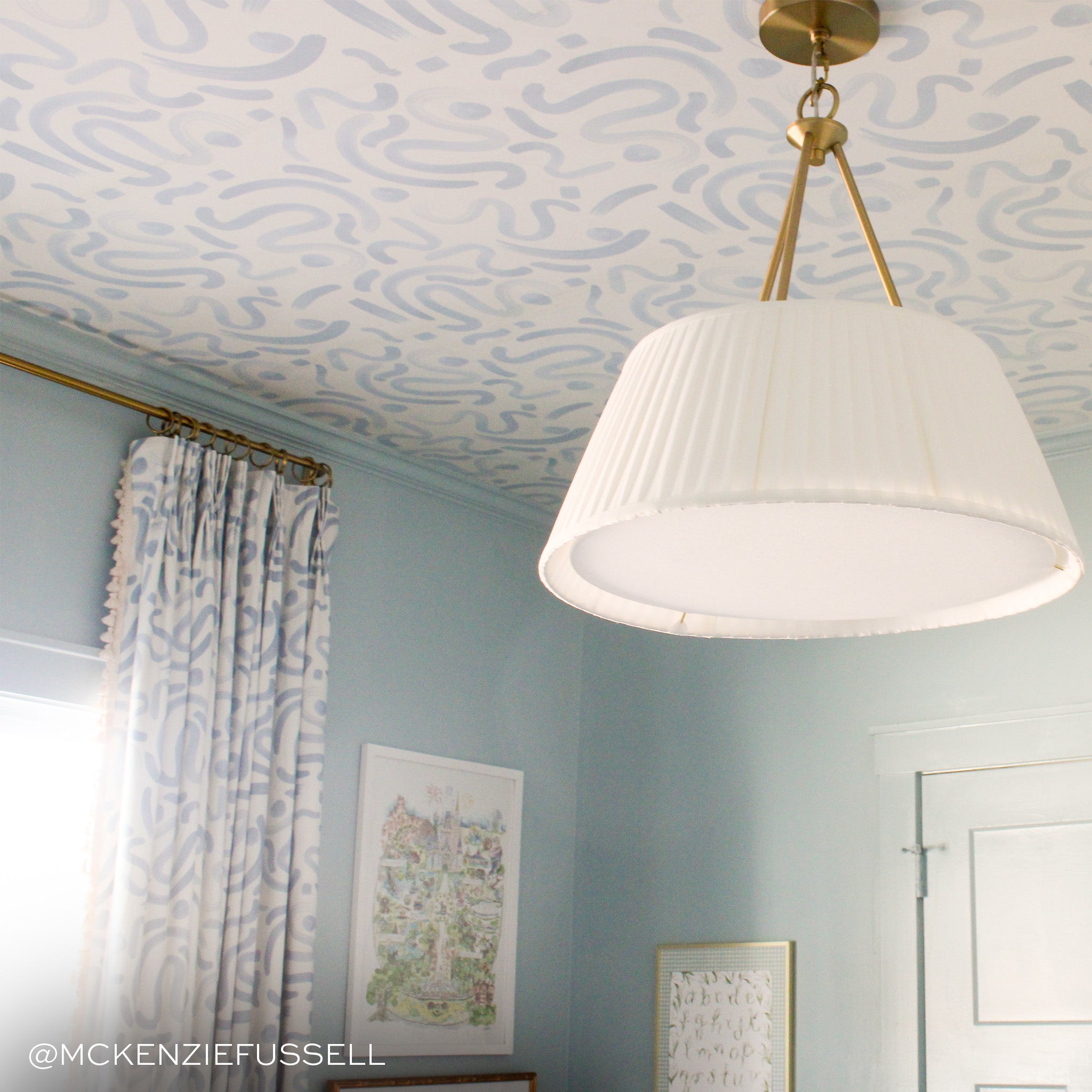 sky blue abstract wallpaper on the ceiling with light blue painted walls and a white and gold light fixture