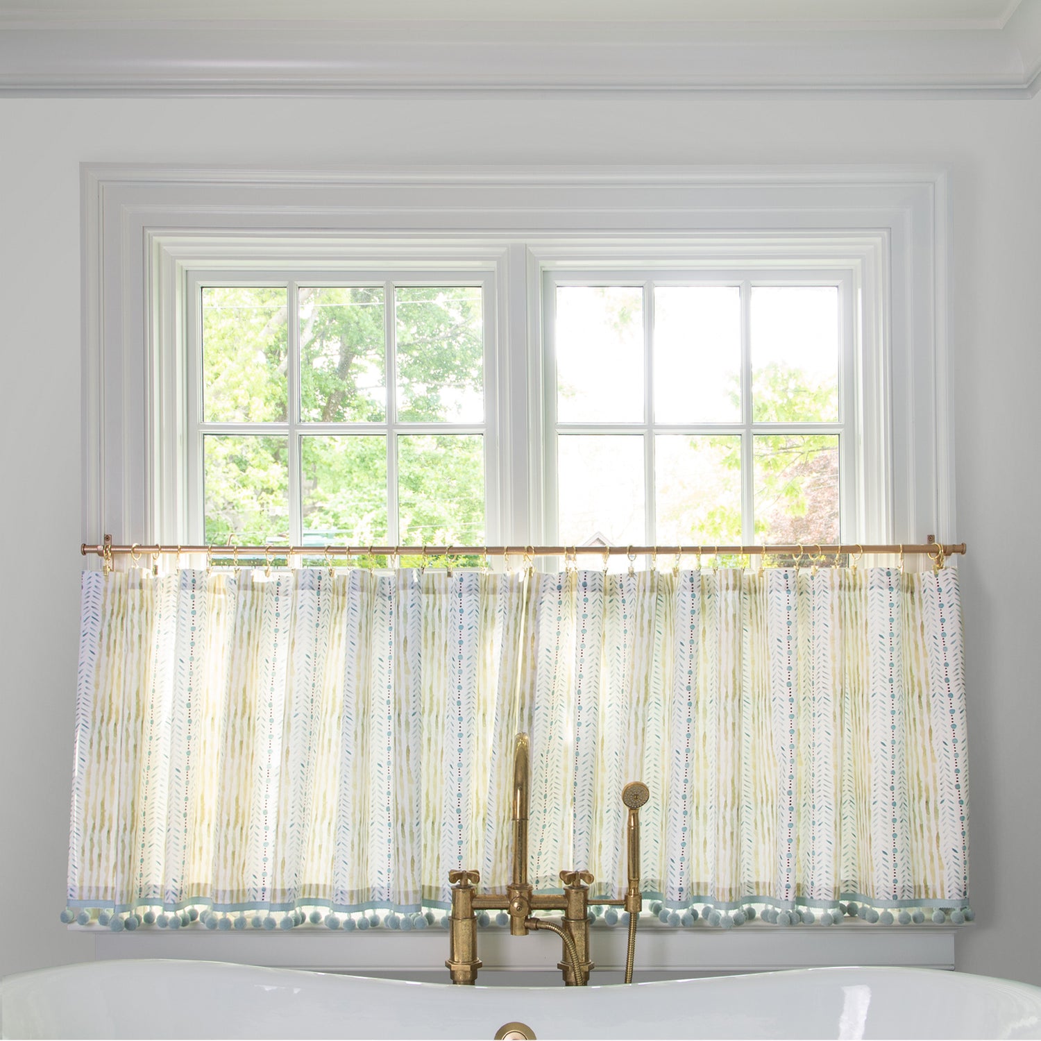Blue & Green Striped Printed Cotton fabric curtain on a metal rod in front of an illuminated window in a bathroom