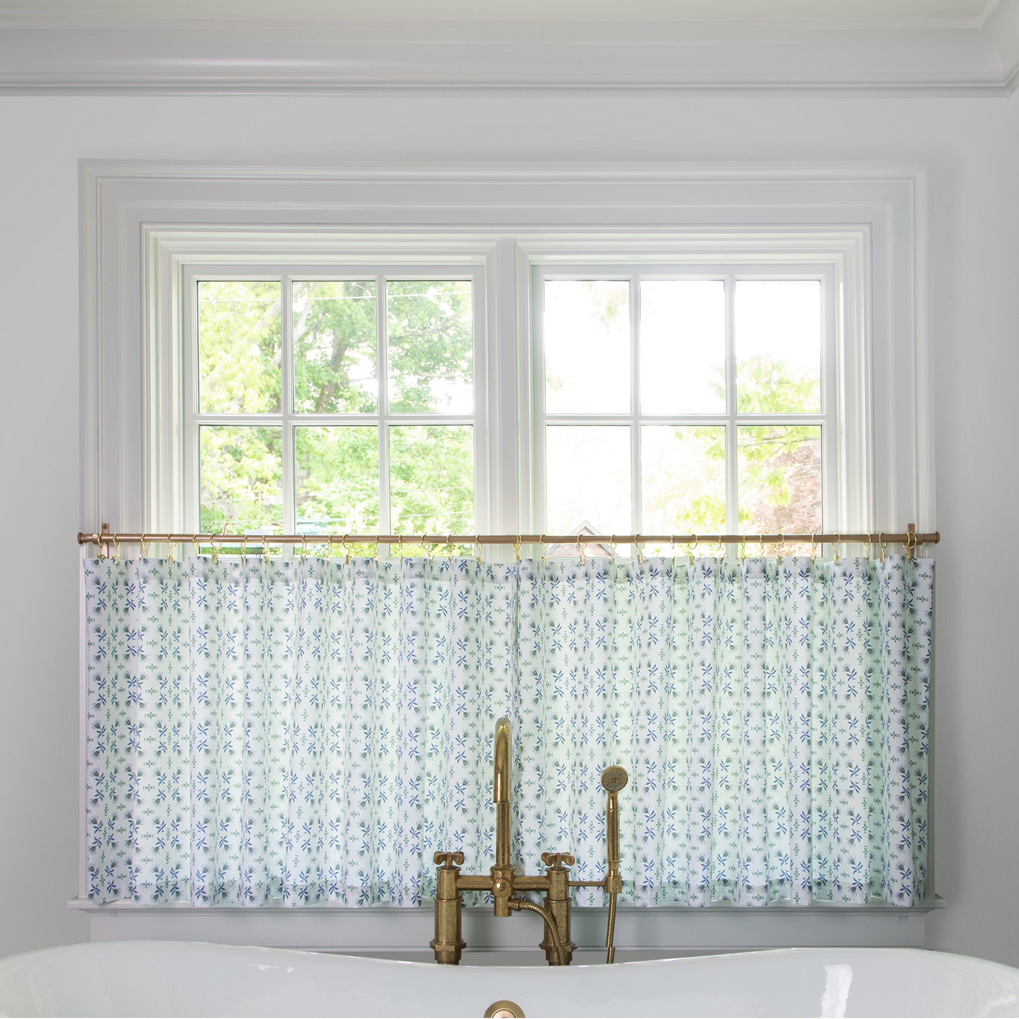  Blue & Green Floral Printed curtain on a metal rod in front of an illuminated window in a bathroom