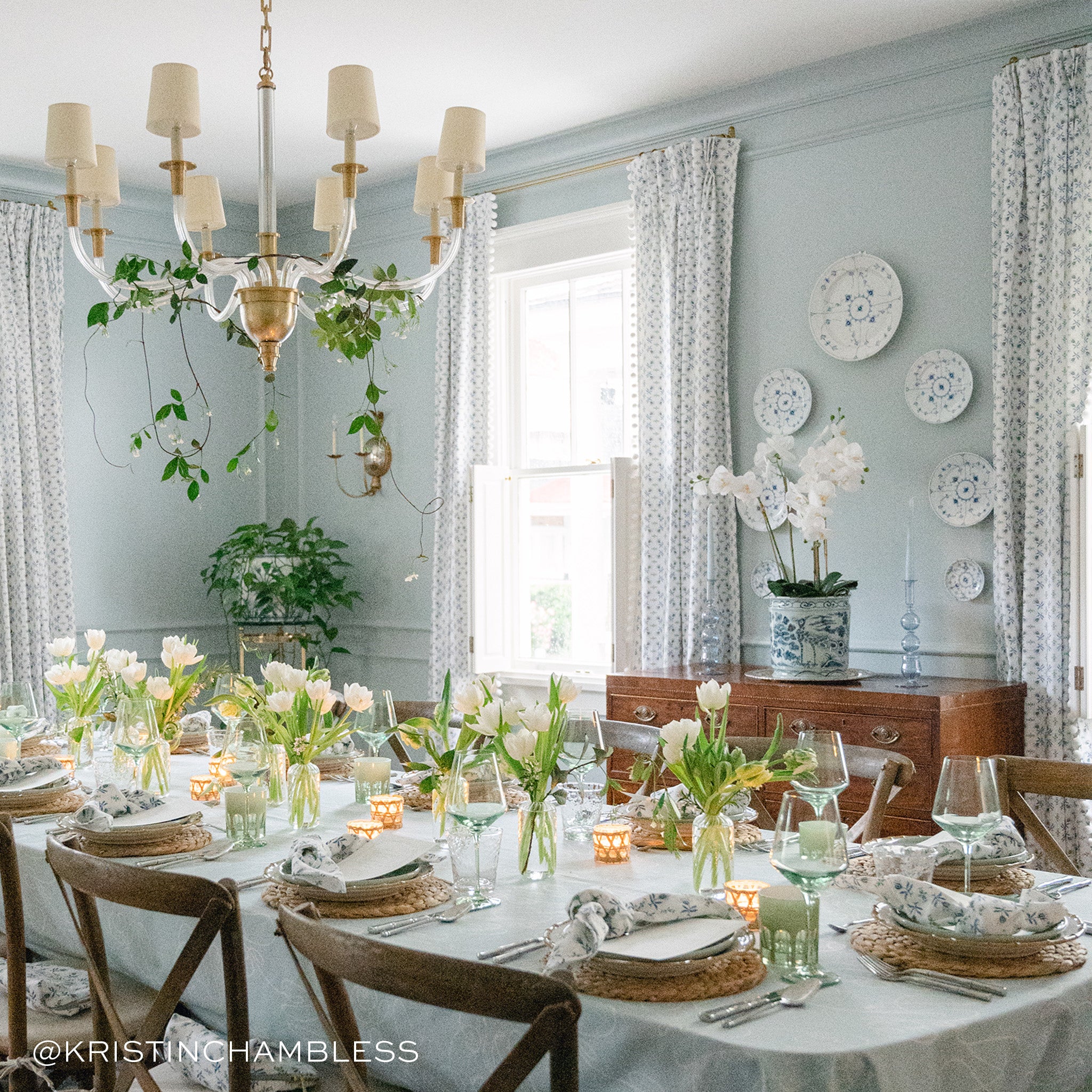 Dining room with white chandelier styled with Blue & Green Floral Printed Curtains. Photo taken by Kristin Chambless